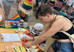 A person signs a form on an information table.