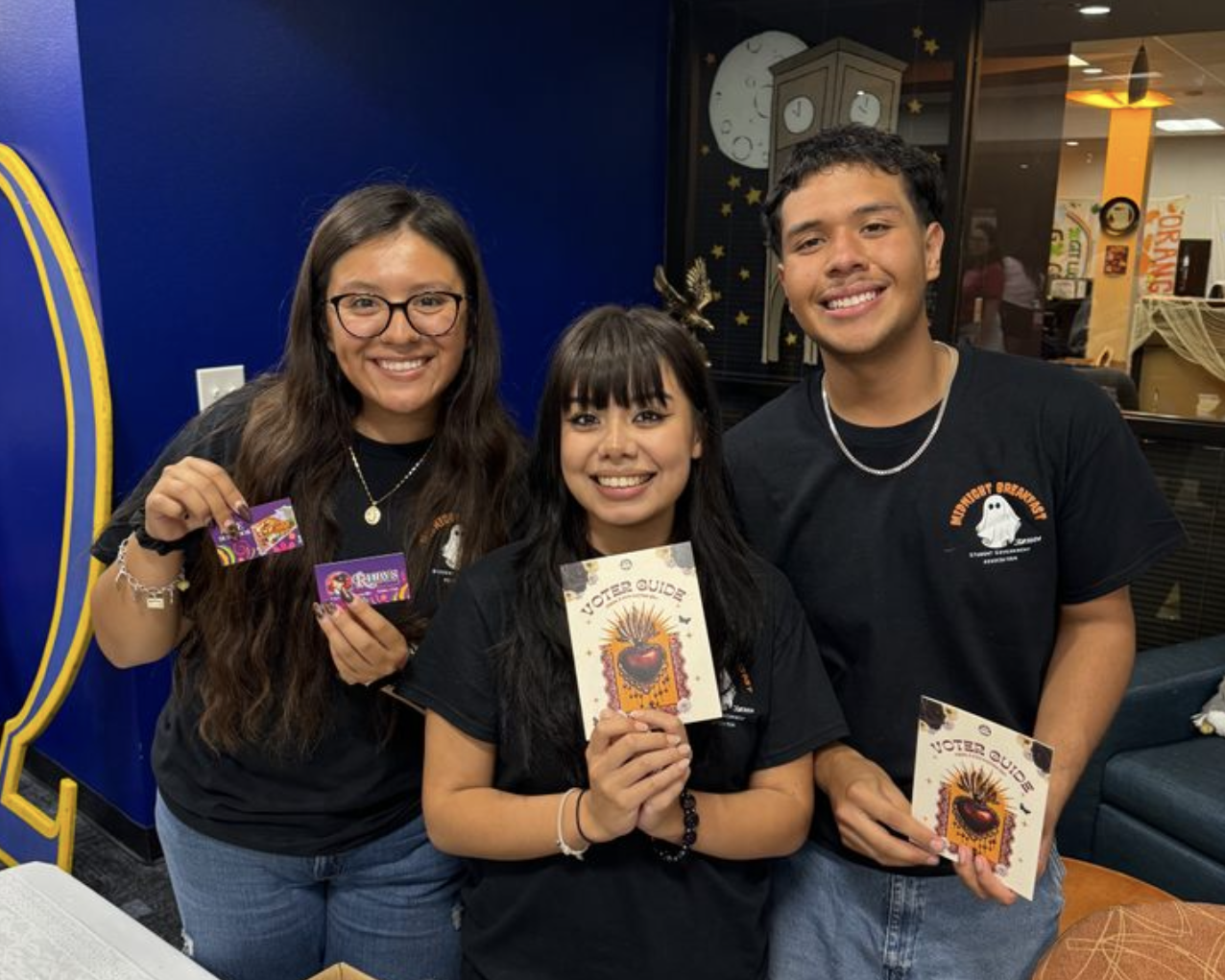 Three people stand together and hold up marketing material.