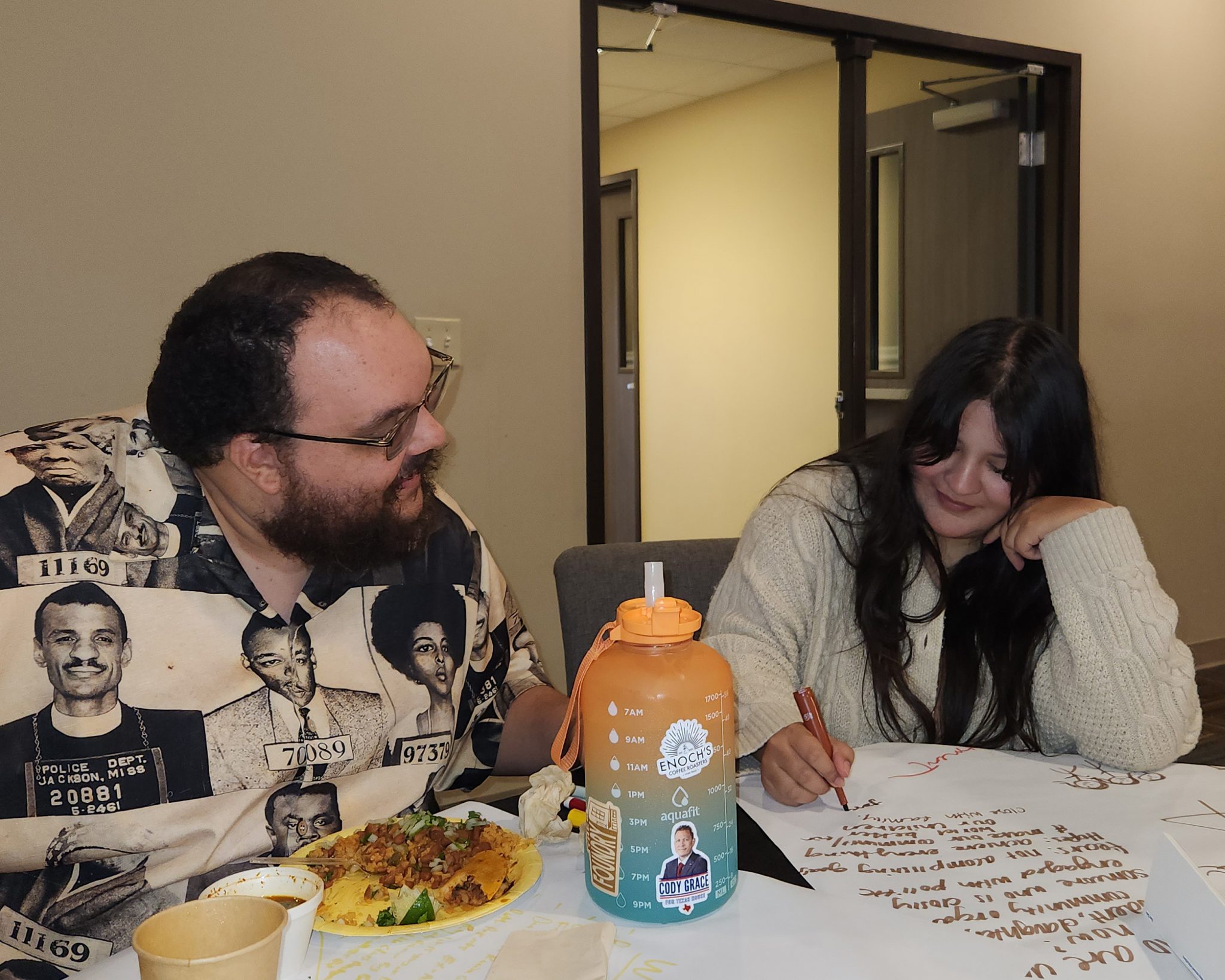 A young man and woman sit at a table together.