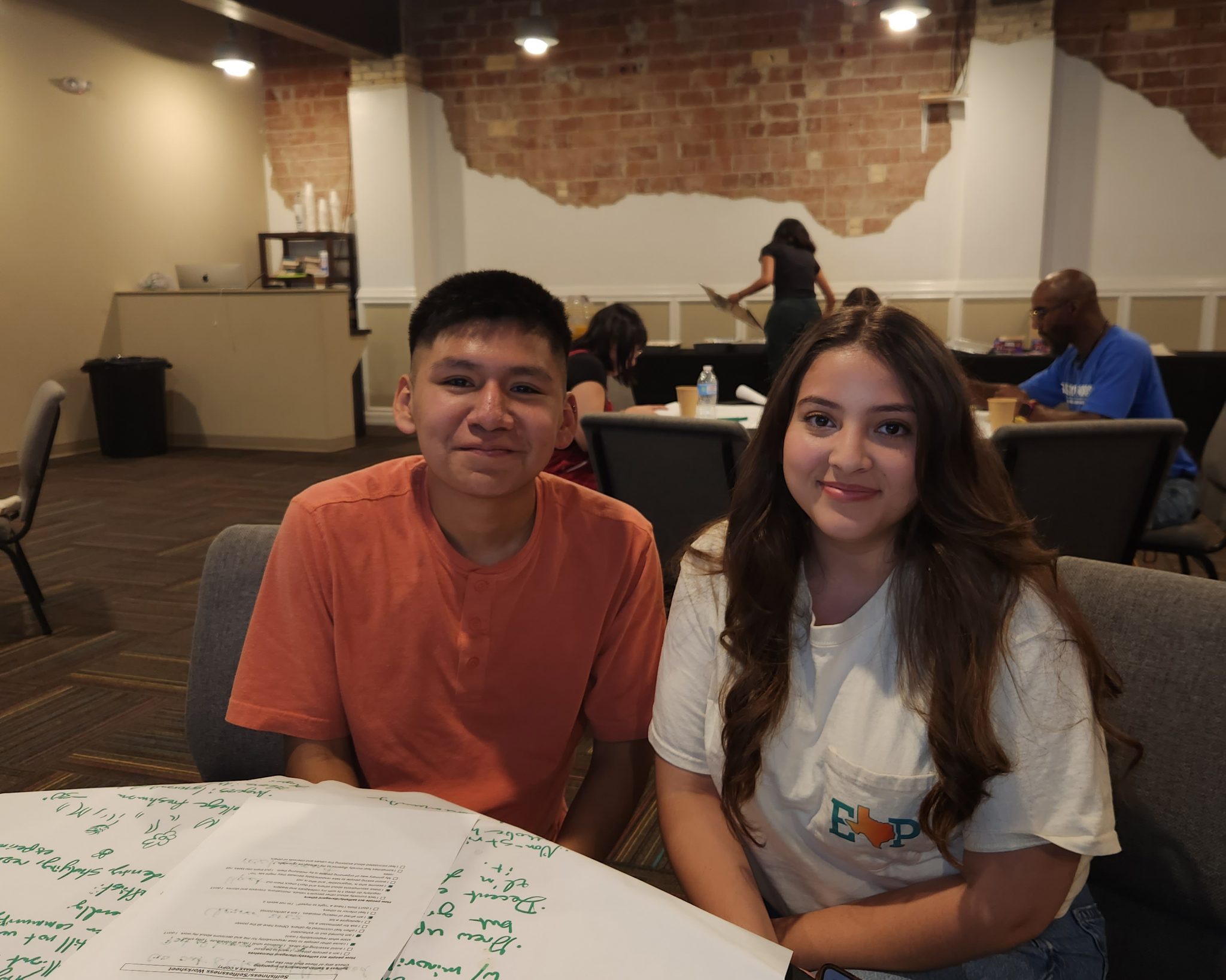 A young man and woman sit at a table together.